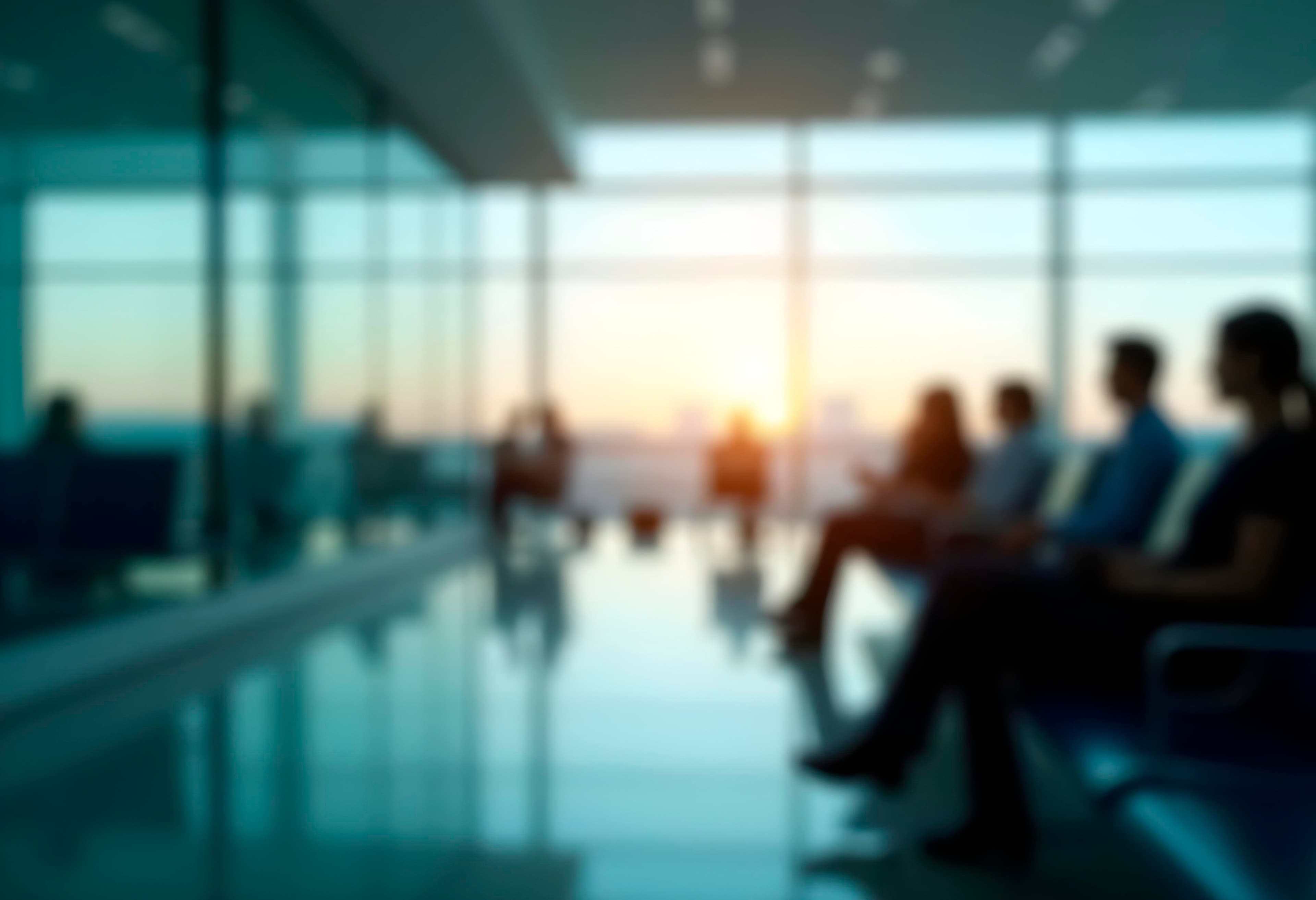 Blurred view of a team seated together in a sunlit office lobby at sunset